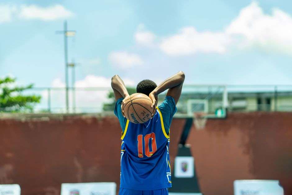 A basketball player wears a numbered jersey on an outdoor court