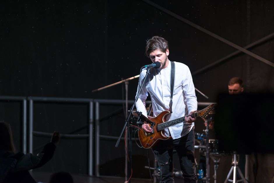 A musician plays electric guitar during a live rock performance at a music venue