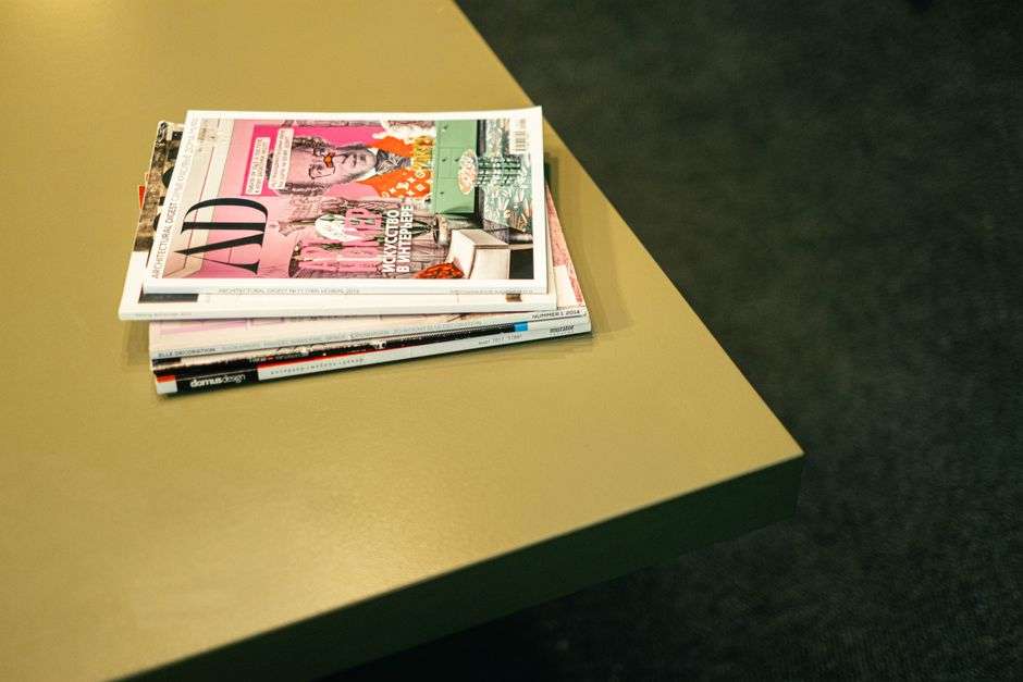 A stack of colorful local magazines displayed in a media office workspace