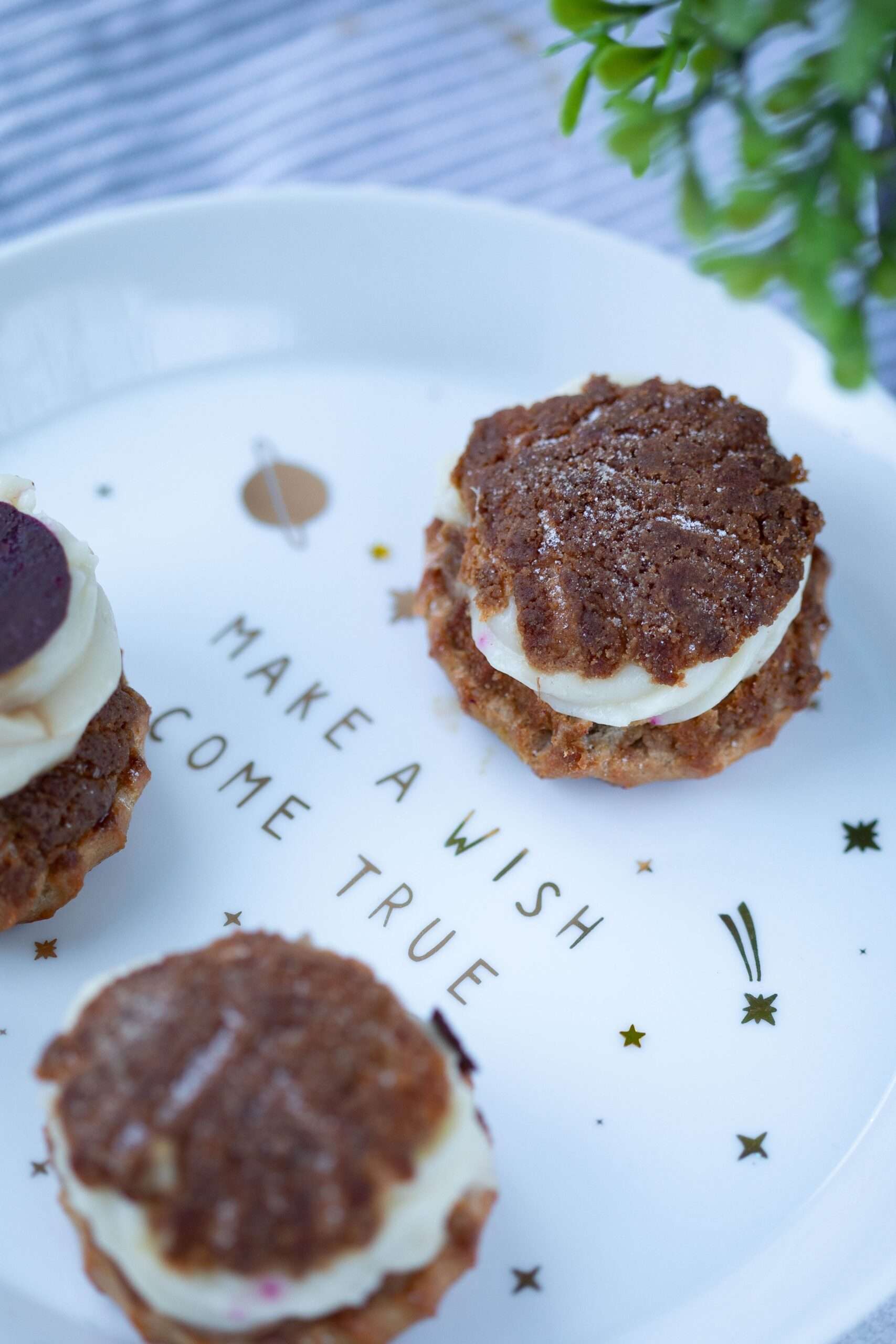 Round chocolate-coated marshmallow sandwich treats stacked on a plate