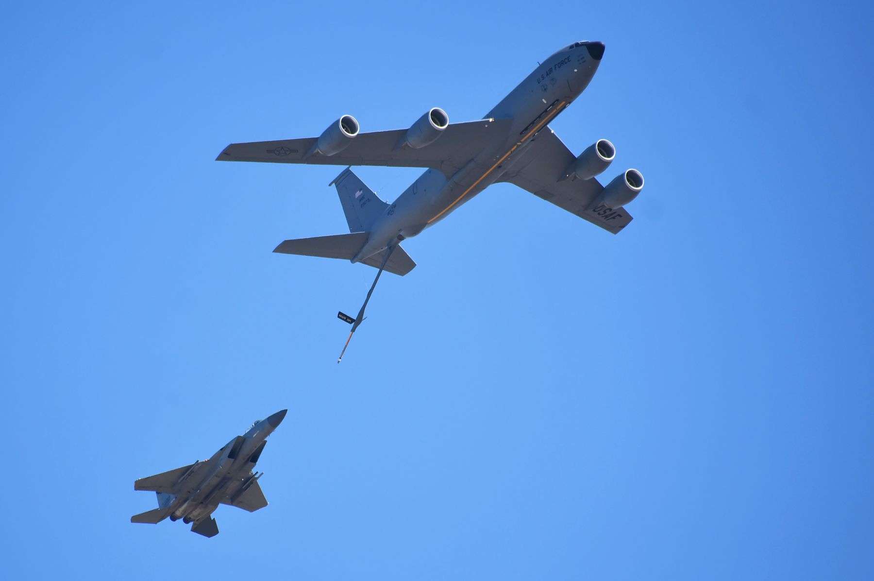 Military aerial refueling tanker aircraft in flight against a clear blue sky