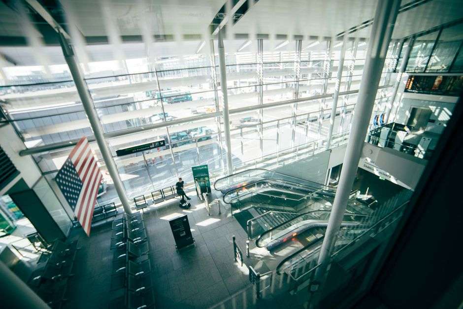 Interior view of an airport terminal with escalators and passenger seating