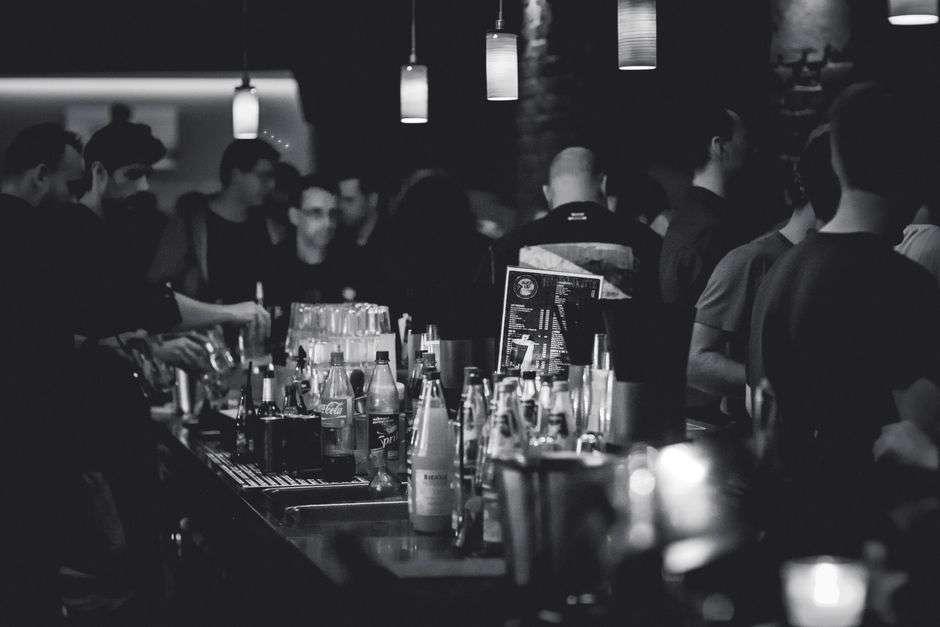 Patrons gather at a crowded bar counter at night