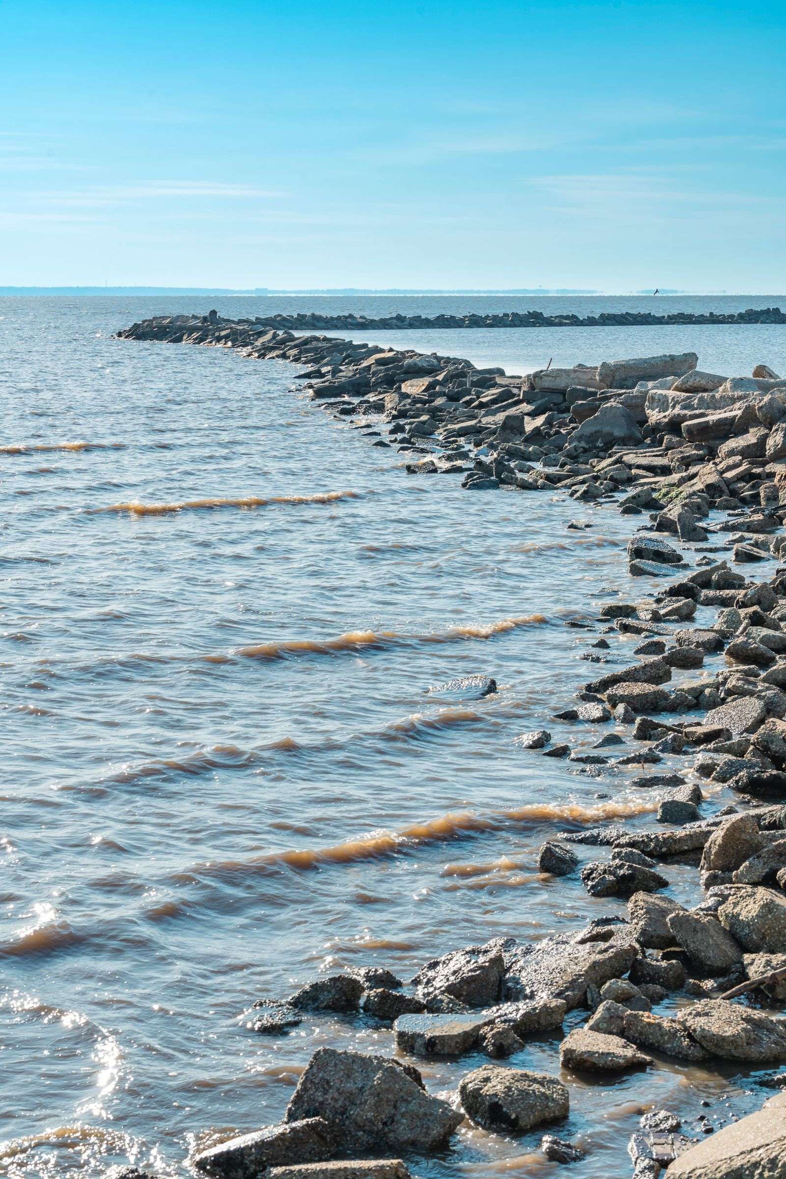 Rocky breakwater and calm water along the Mobile Bay shoreline