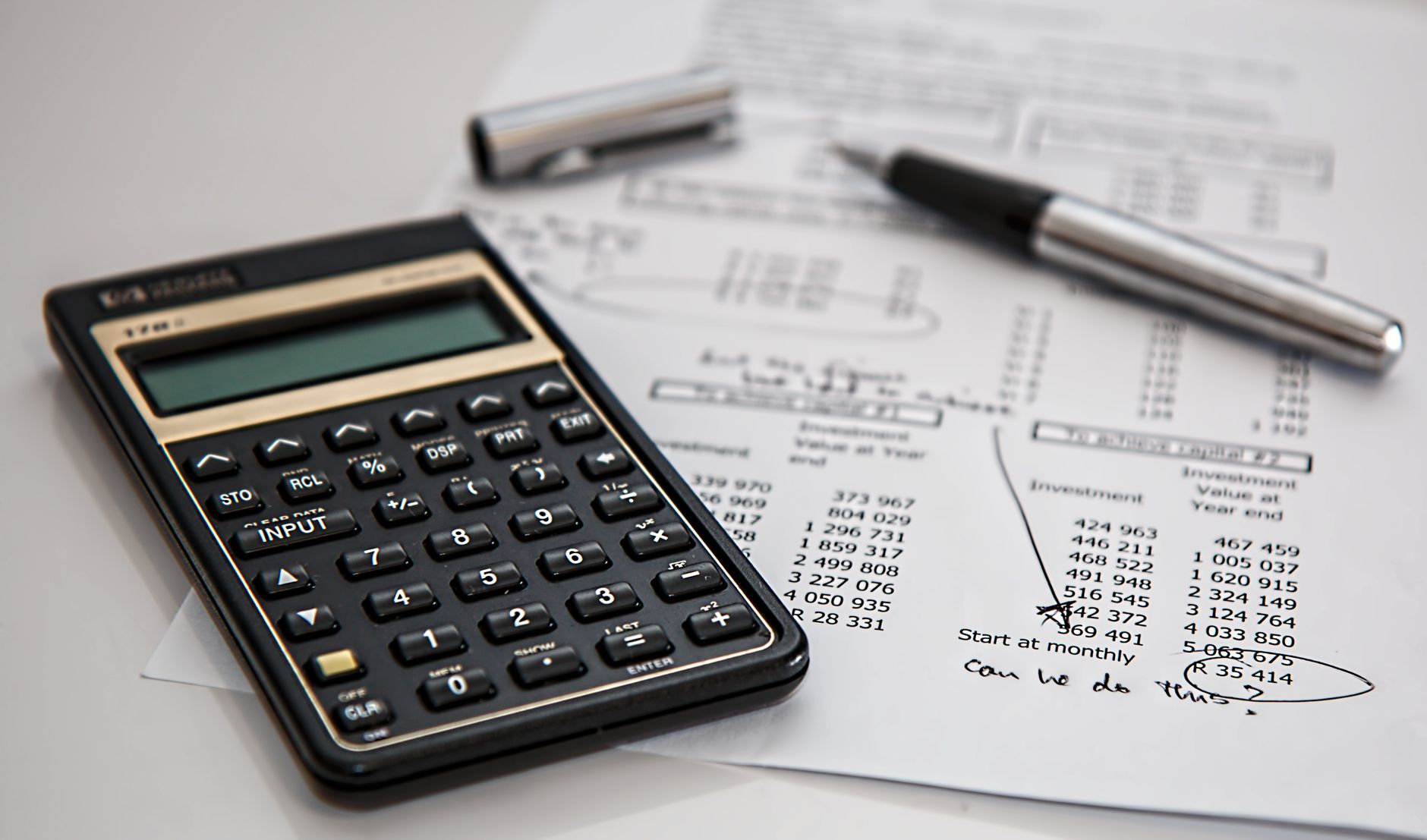 A calculator resting on financial documents and spreadsheets