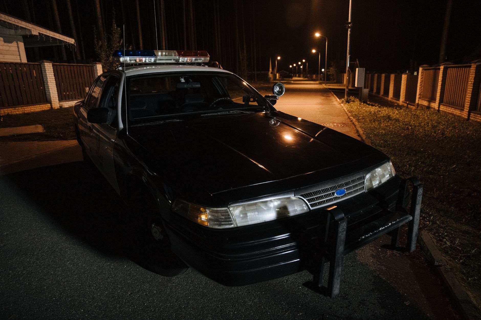 A police car parked on a quiet residential street at night