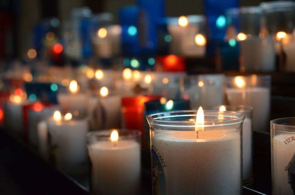 Rows of lit prayer candles inside a church sanctuary