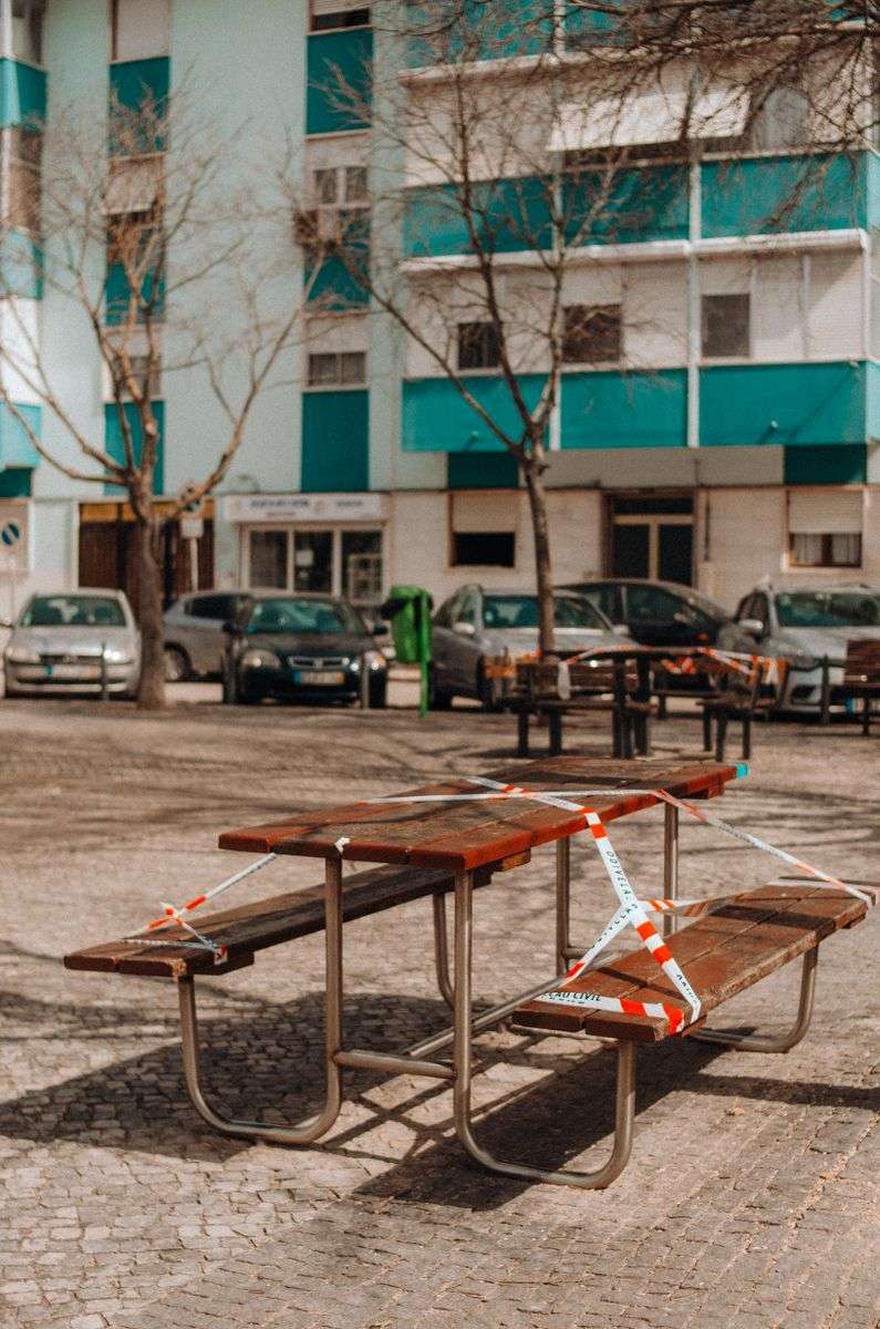 A park picnic table wrapped in barricade tape to prevent public congregation