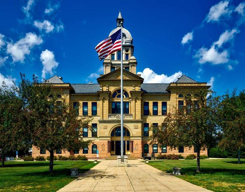 A county courthouse building with an American flag flying, representing local government administration