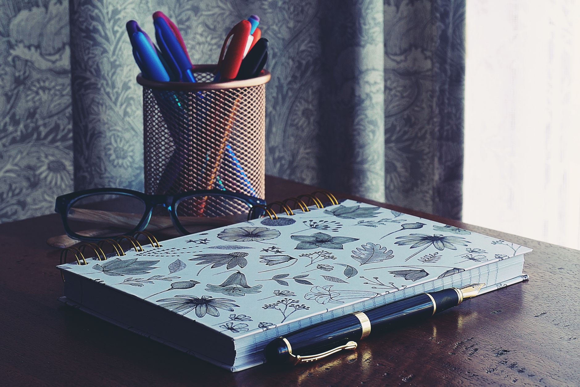 A checkbook and pen resting on a wooden desk