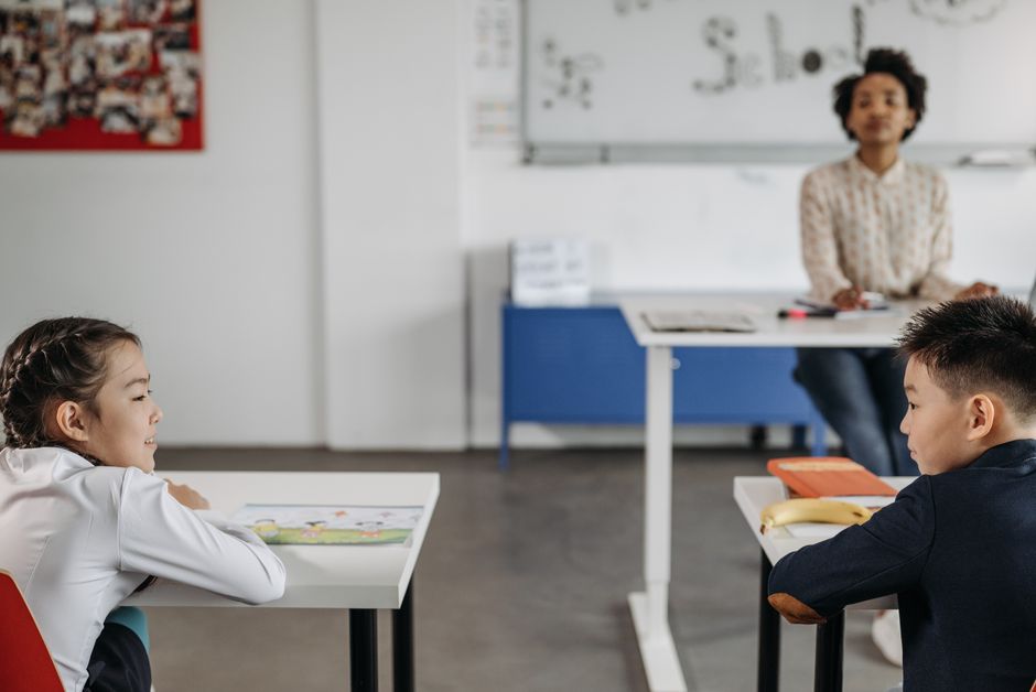 Elementary students working at their desks in a bright classroom
