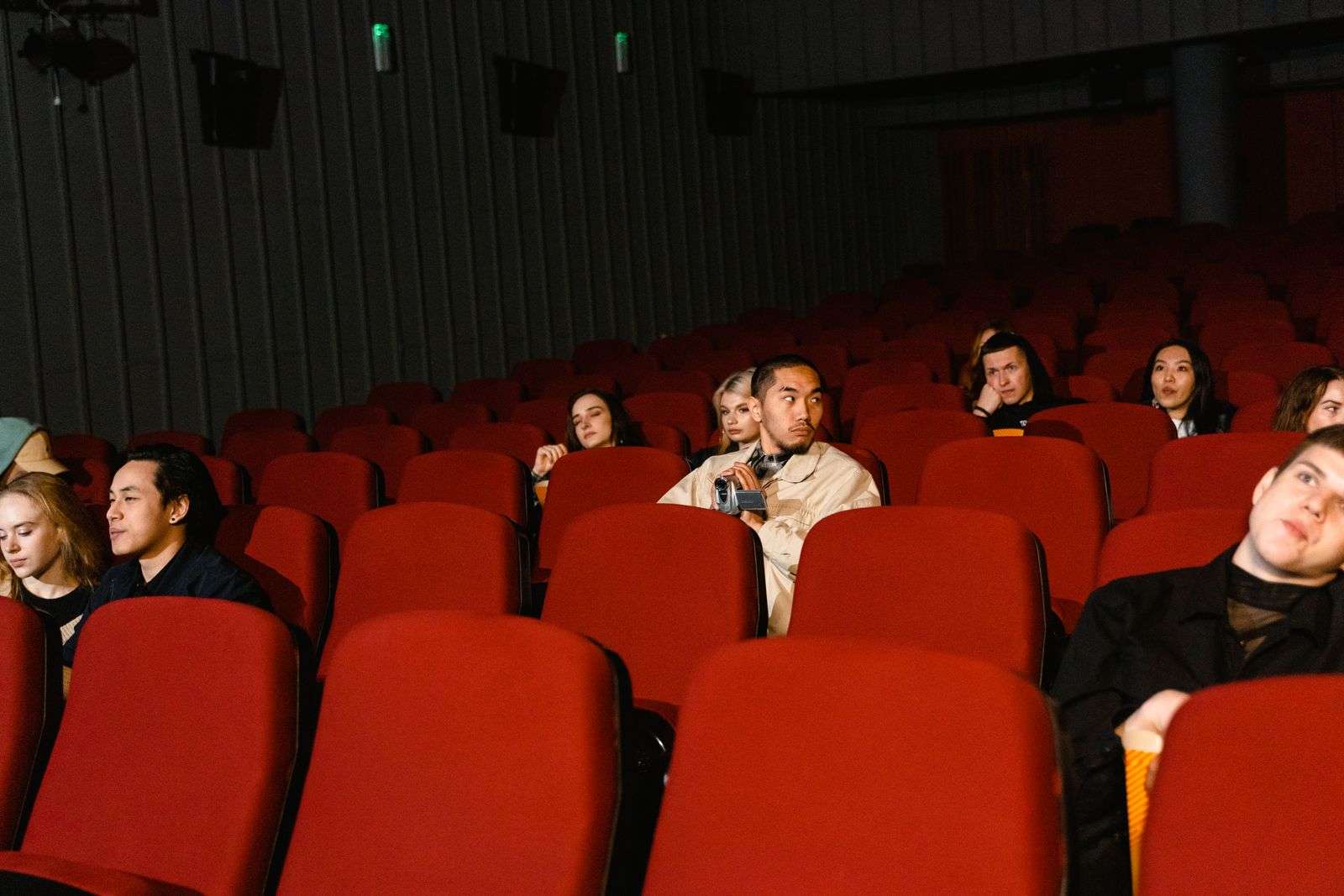 Audience members seated in a theater watching a film on screen