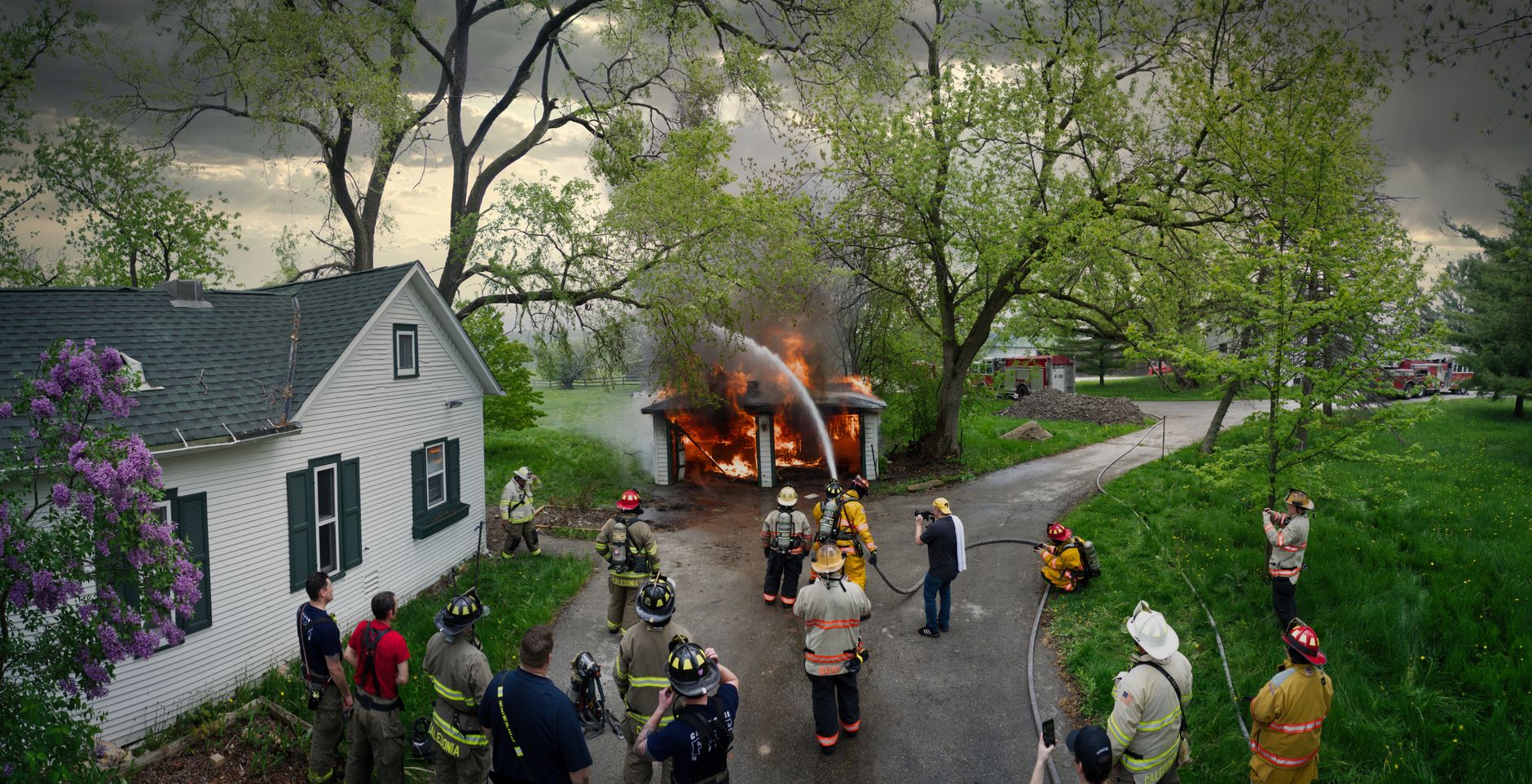 Firefighters in turnout gear working a burning wood-frame house