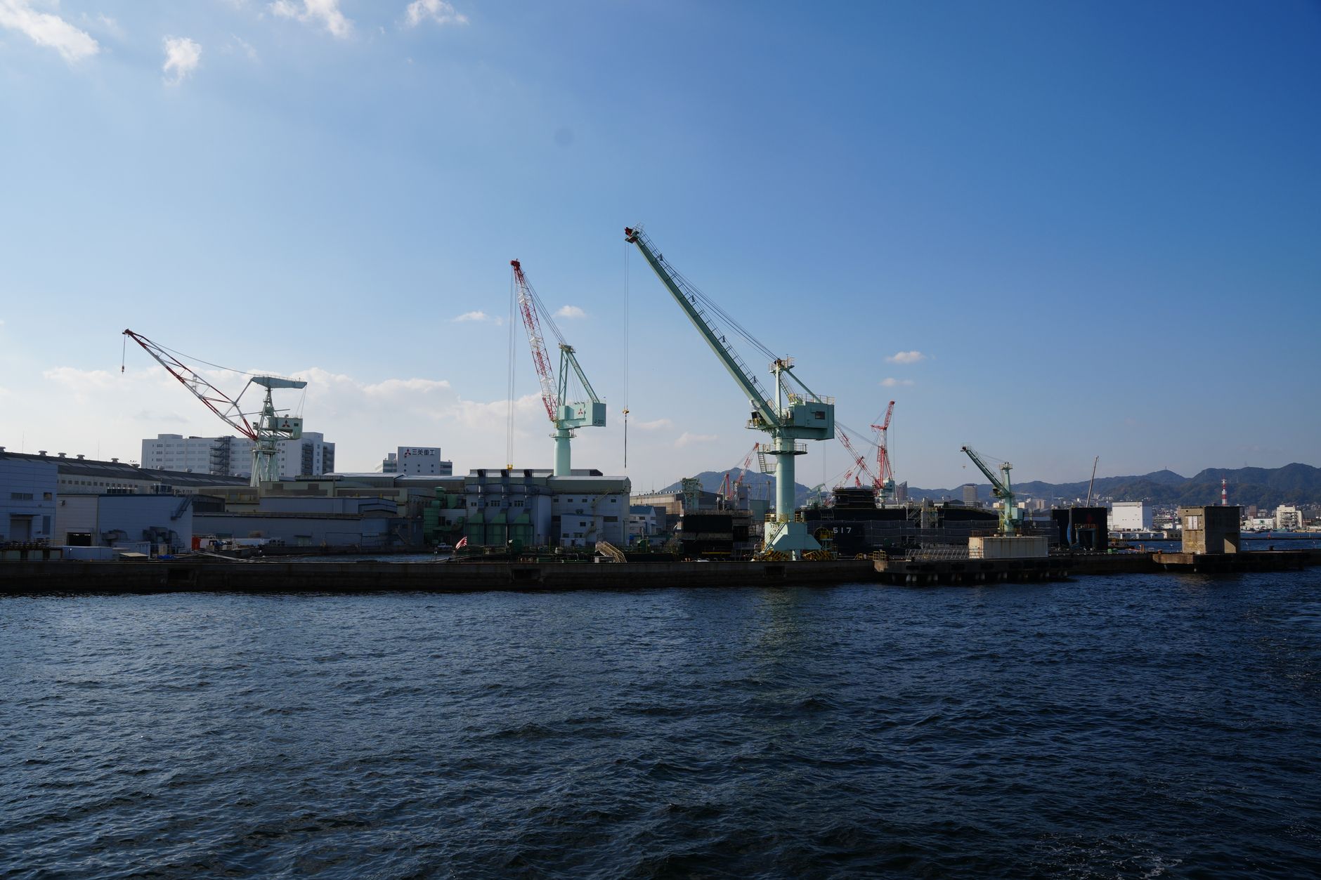 A working port waterfront with cranes and cargo along a river