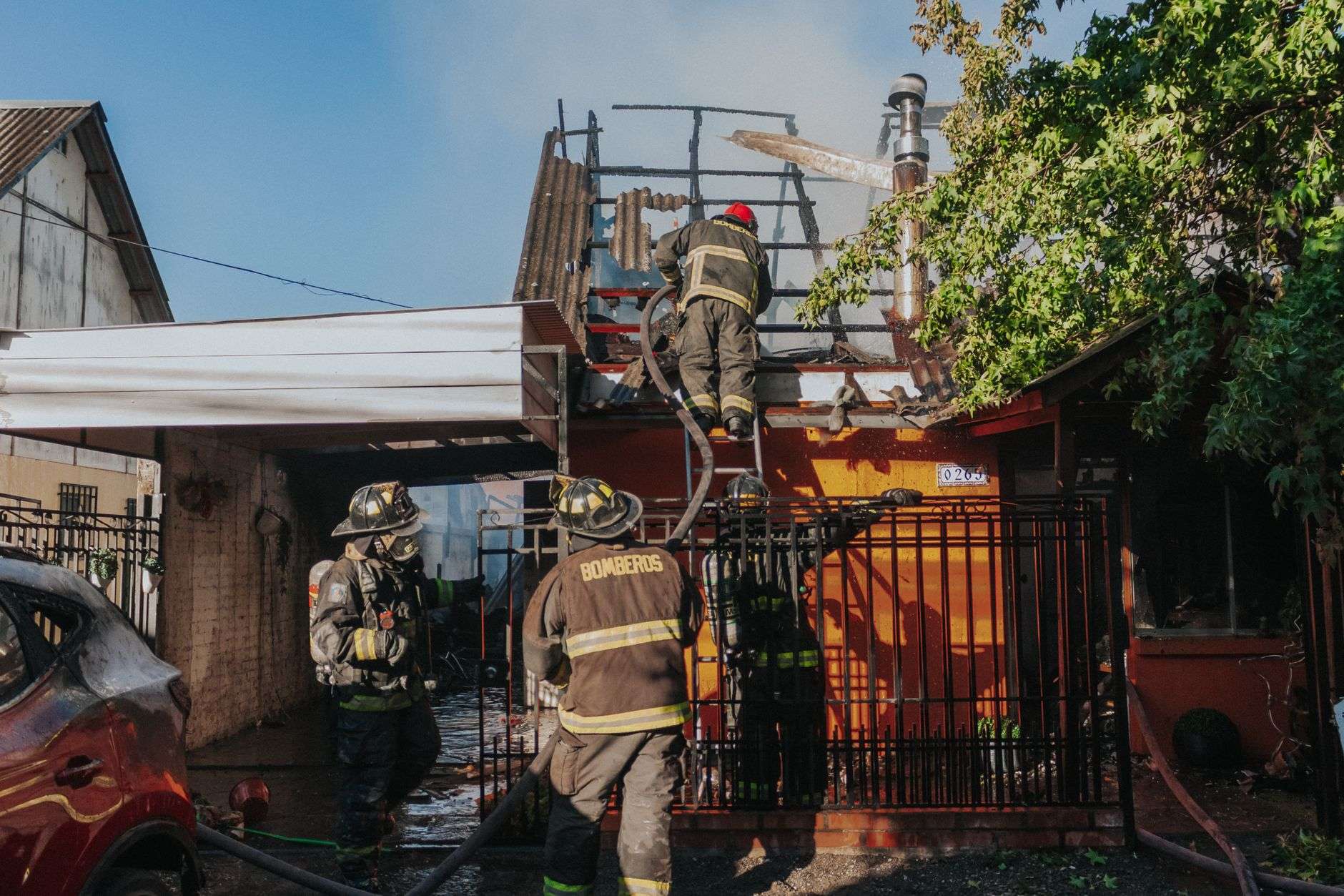 Firefighters battling a residential house fire with hoses