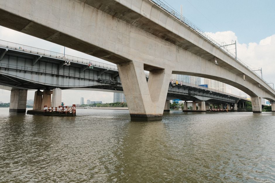 A large bridge crossing a wide river near a downtown skyline