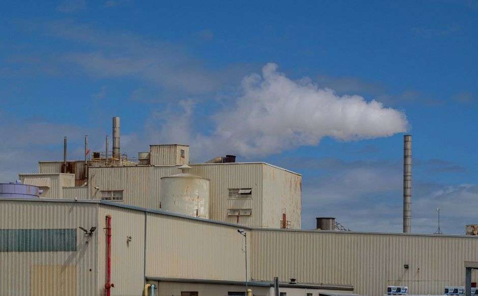 An industrial manufacturing plant with tall smokestacks, similar to a tissue and paper mill