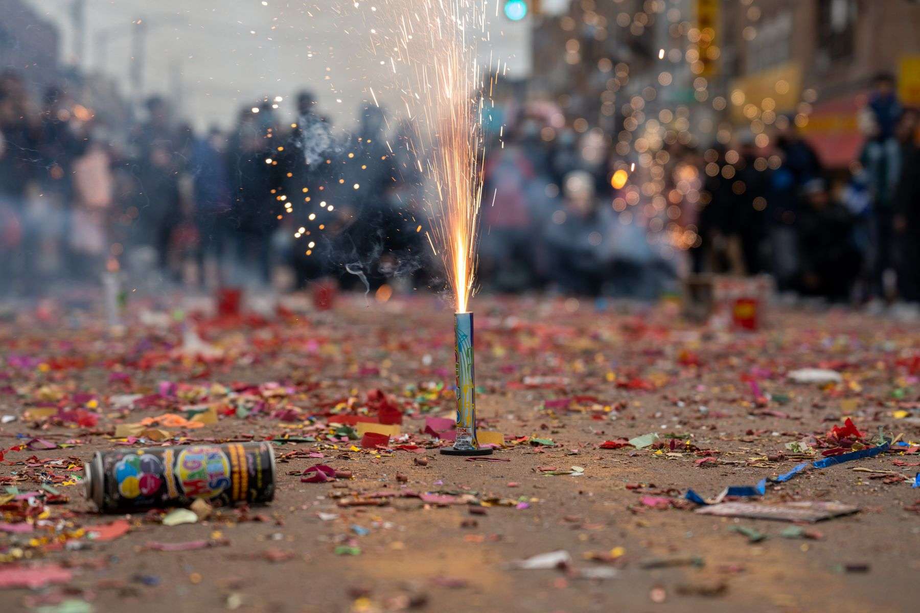 Fireworks and confetti fill the night sky over a downtown street during a New Year's Eve celebration