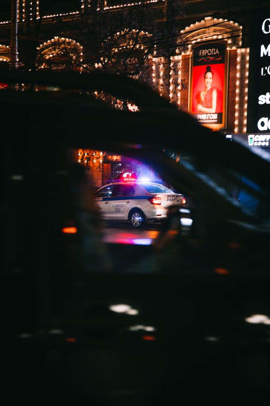 A police car with flashing lights on a city street at night, representative of a police pursuit