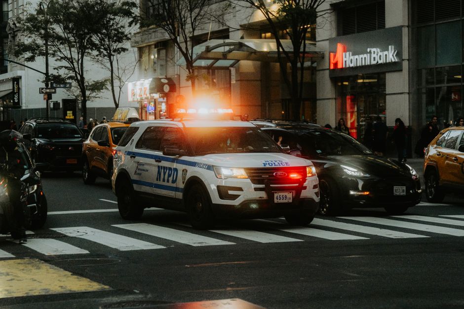 A police patrol car stopped at a busy city street intersection