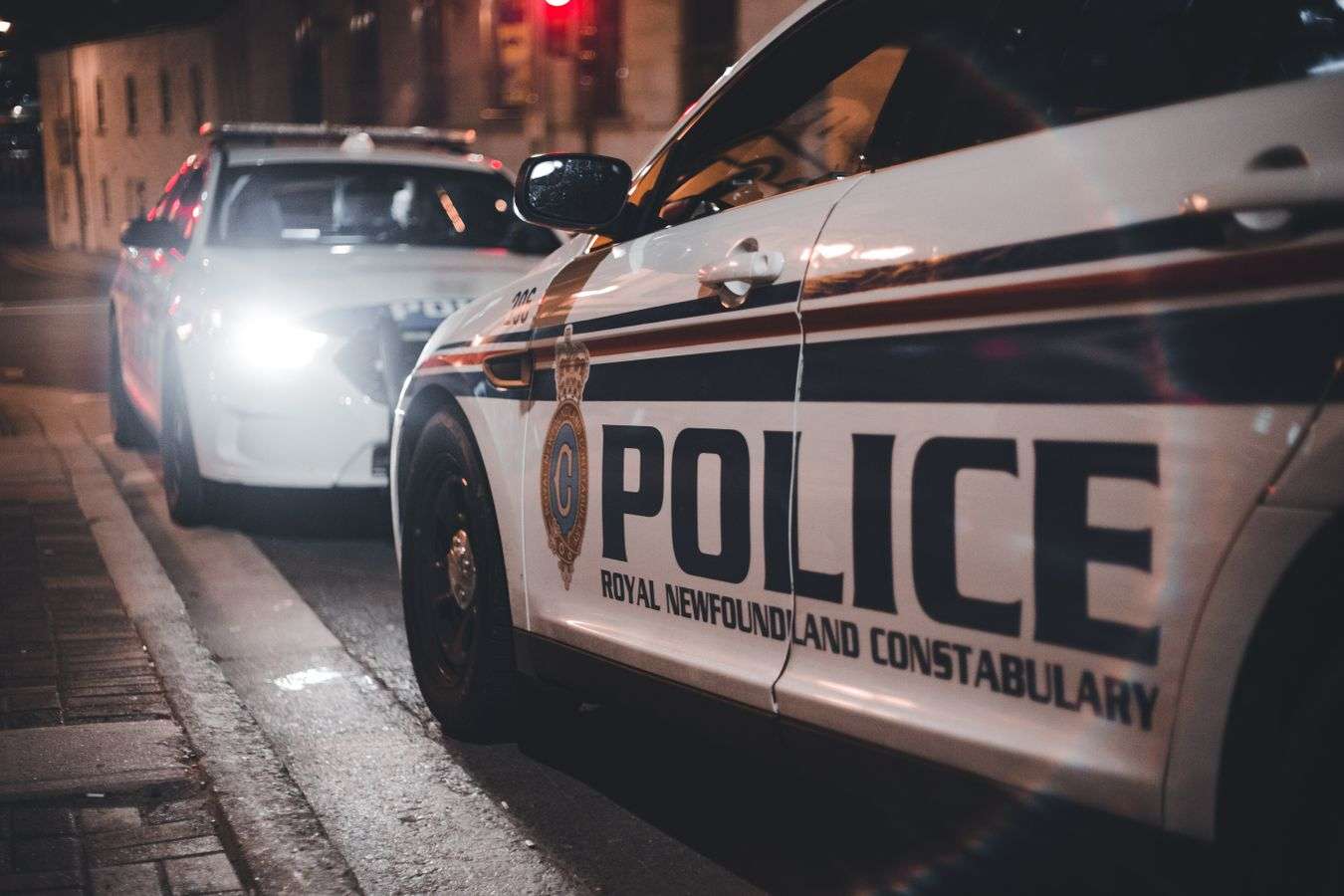 A police patrol car with emergency lights active on a city street at night