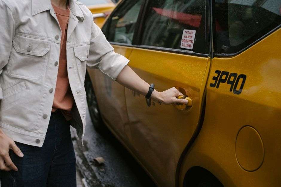 A passenger opens the door of a rideshare vehicle parked on a city street