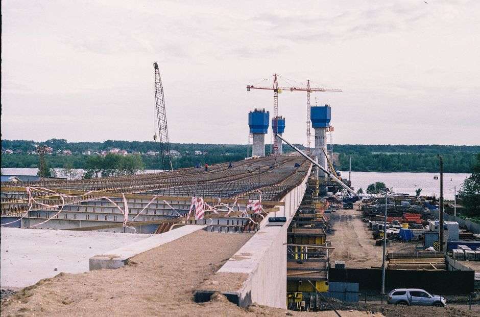 Cranes and construction equipment work on a large bridge span over a river