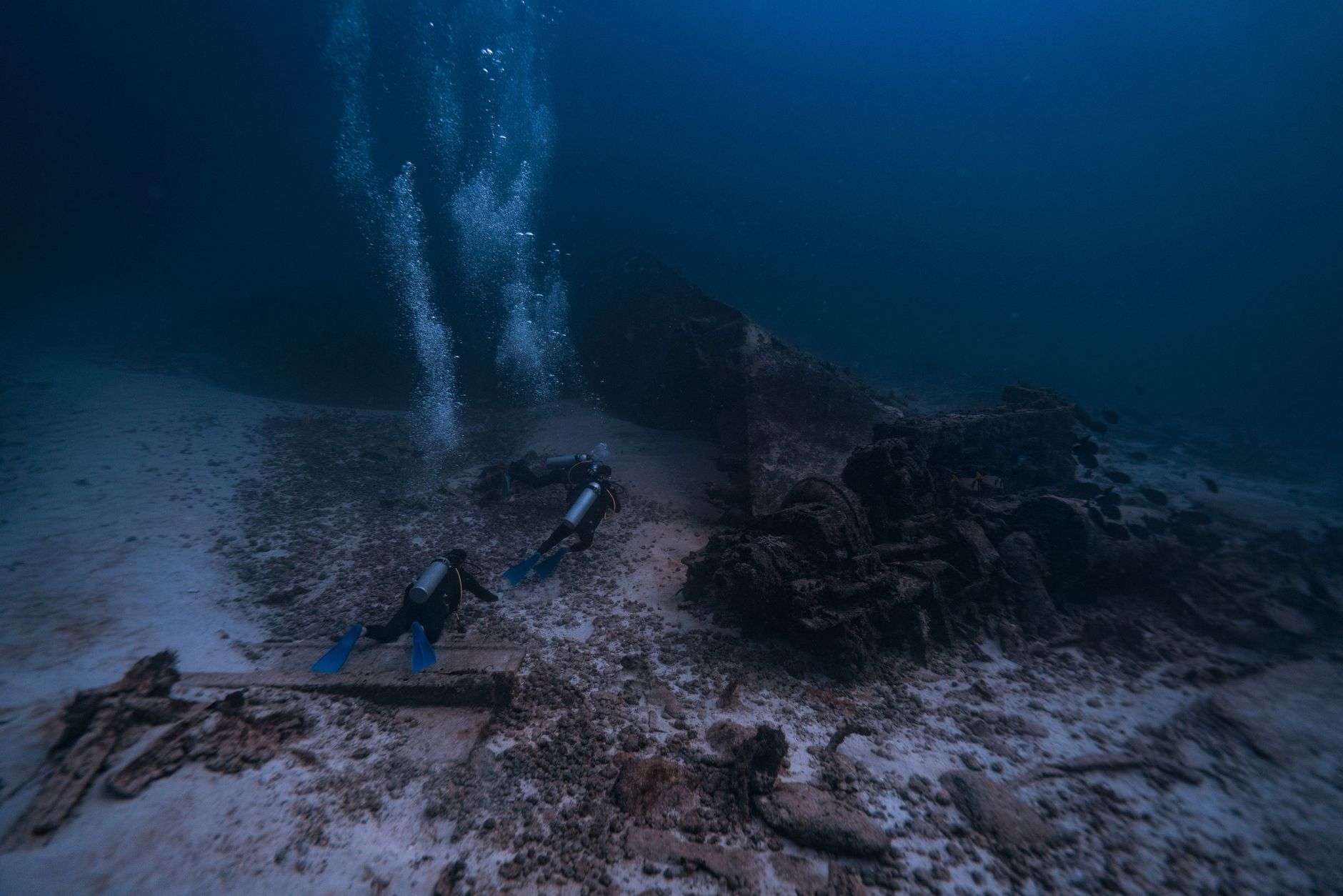Divers examine a submerged shipwreck during an underwater archaeological survey