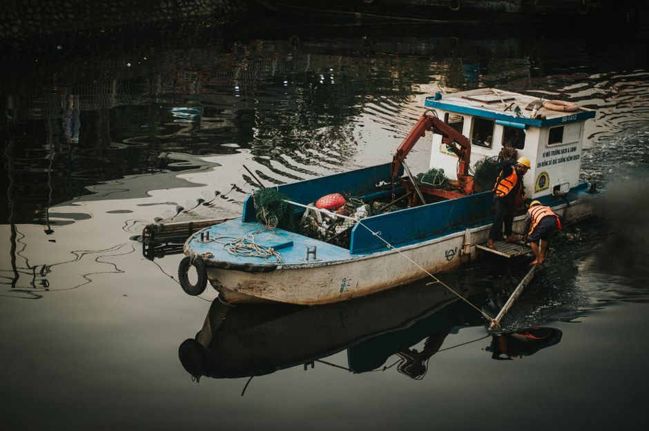 A boat collecting floating debris from a river waterway