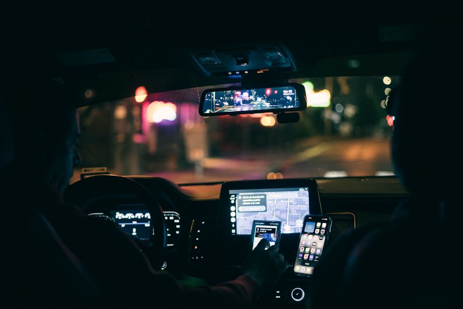 A rideshare driver sitting behind the wheel of a car on a city street
