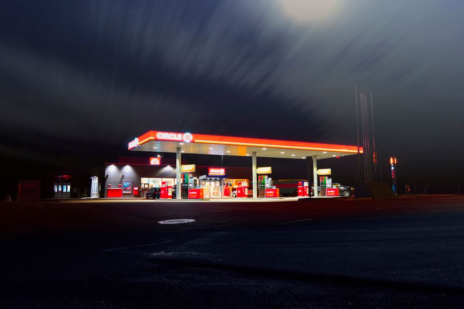A brightly lit gas station forecourt and convenience store at night