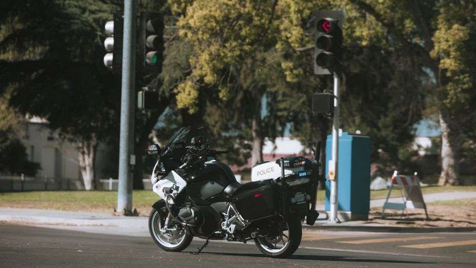 Motorcycle parked on a roadway shoulder with emergency lights in the background