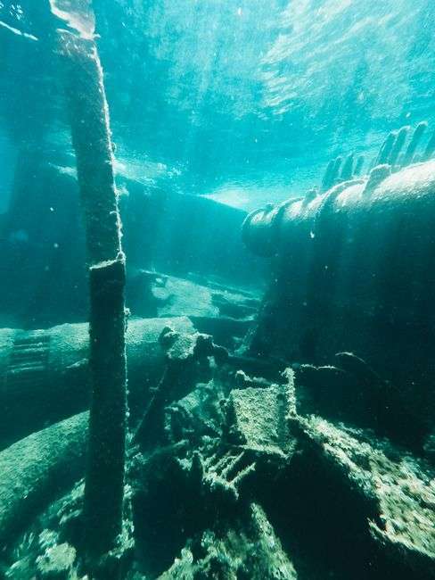A large sunken ship resting on the Gulf floor as an artificial reef, with divers exploring nearby