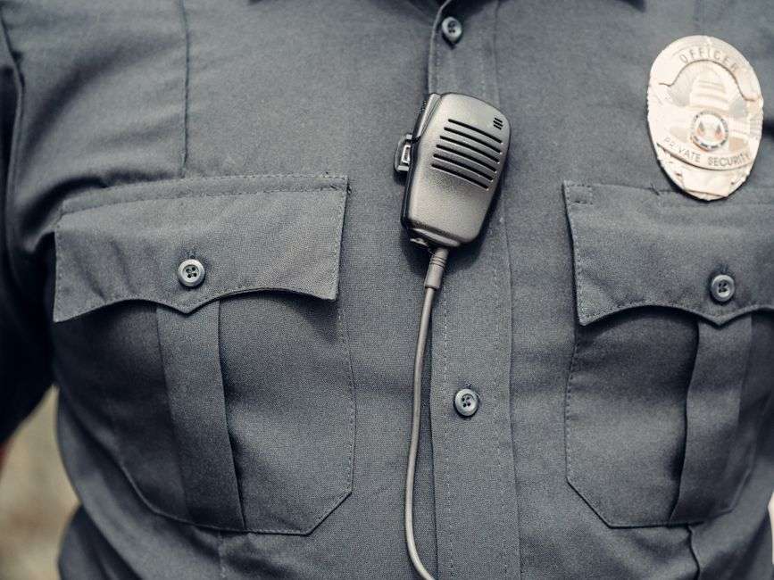 Close-up of a law enforcement officer's uniform showing a body camera and badge