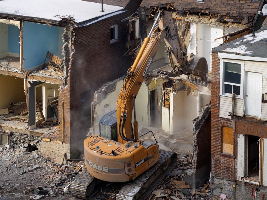 An excavator demolishing an abandoned house