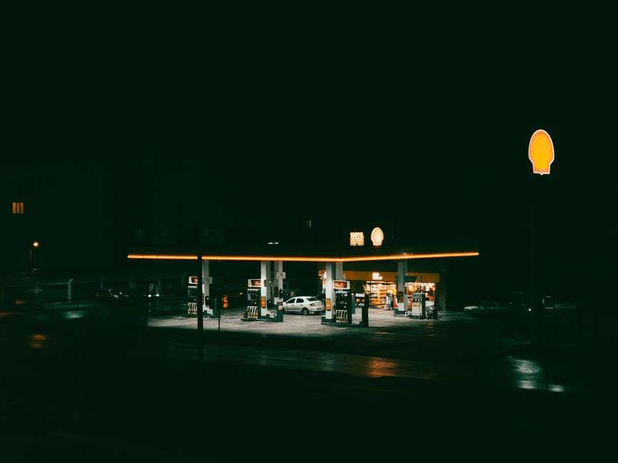 A gas station illuminated at night along a roadway