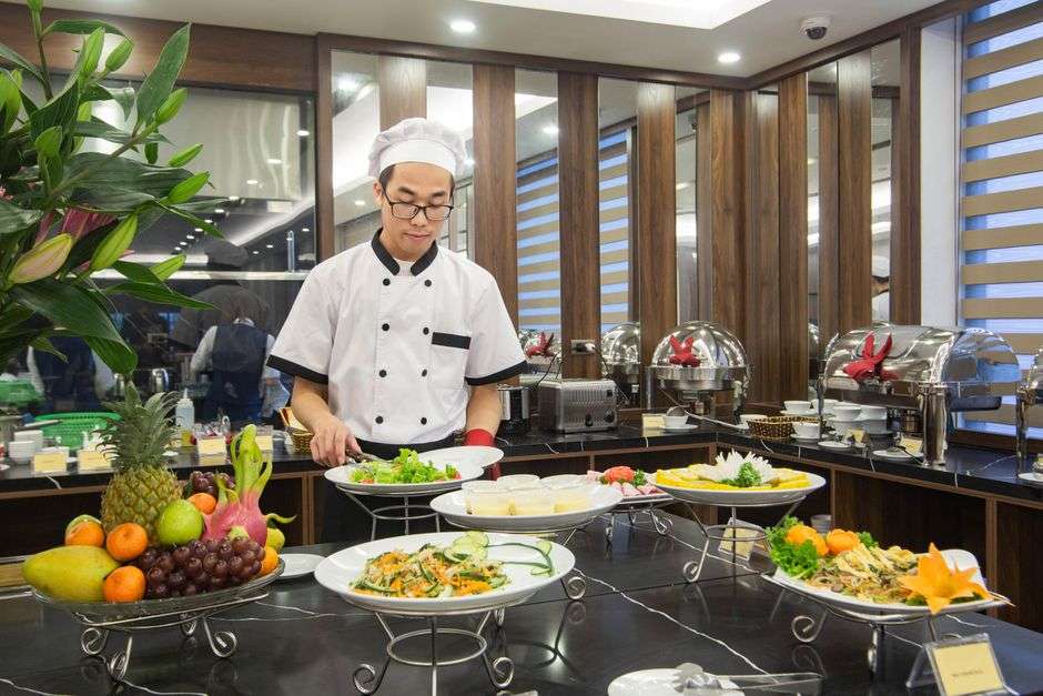 A chef preparing food in a hotel kitchen and dining area