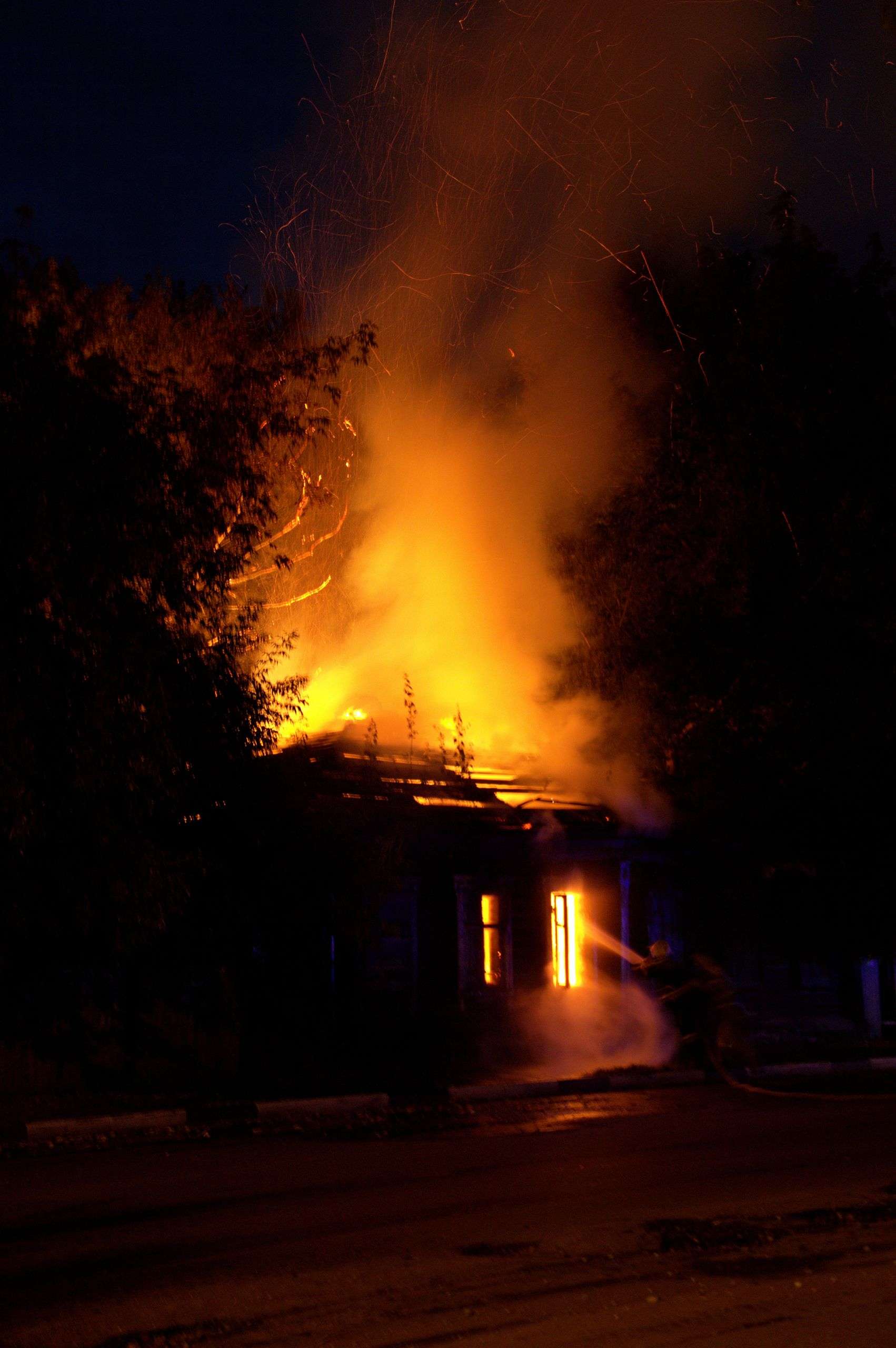 Firefighters battling a house fire at night with heavy smoke and flames