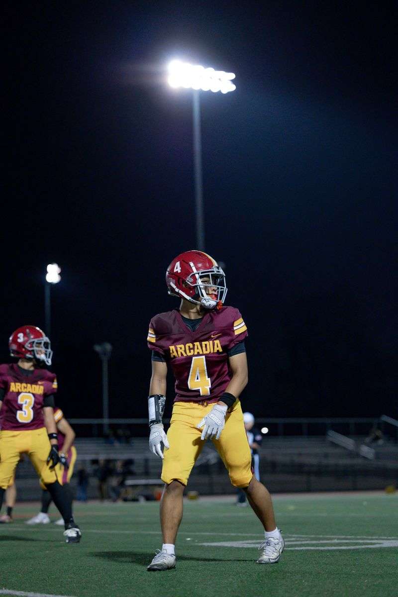 High school football player under bright stadium lights at night