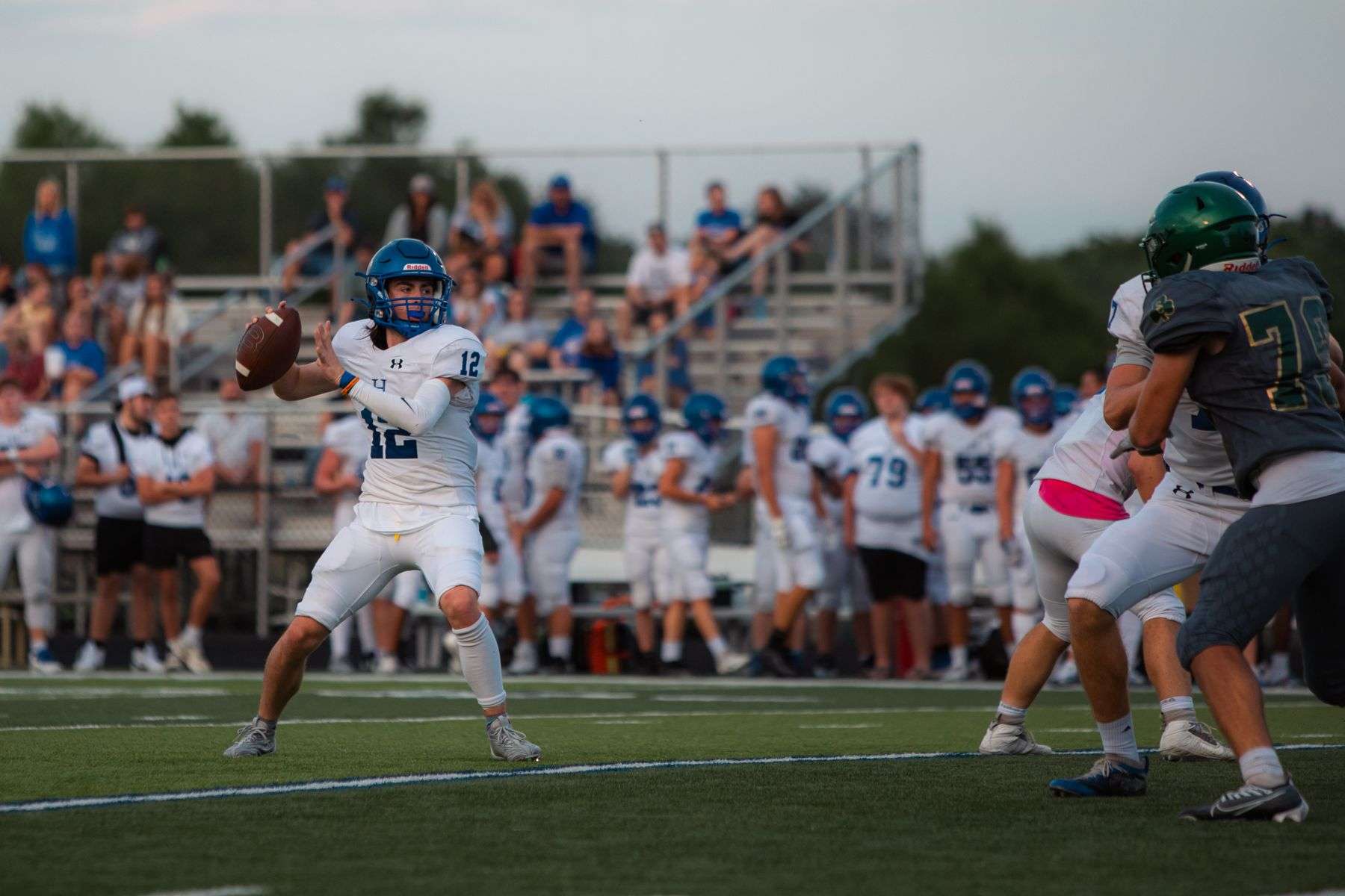 High school football quarterback in uniform preparing to throw a pass during a game