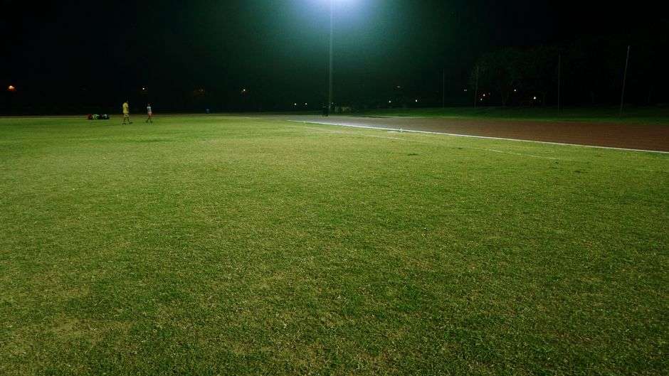 An empty school running track lit up at night