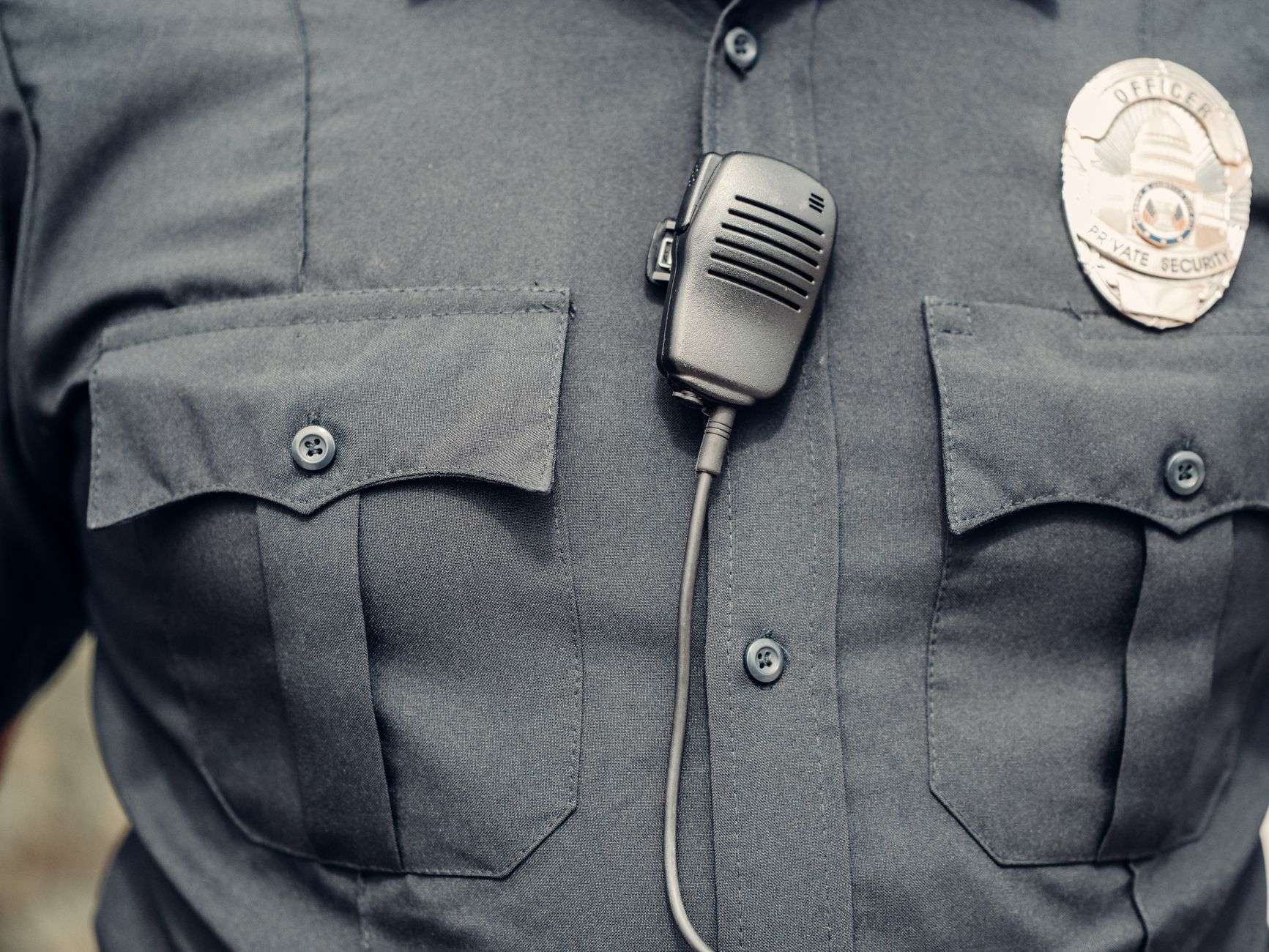 Close-up of a police body camera and badge on an officer's uniform