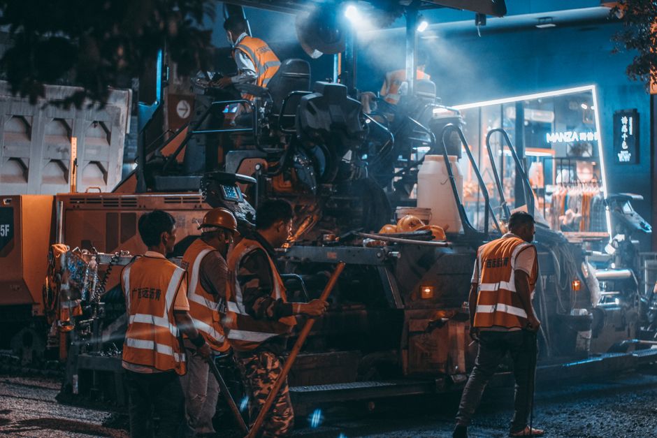 Construction crew repairing a flood-damaged road and drainage system