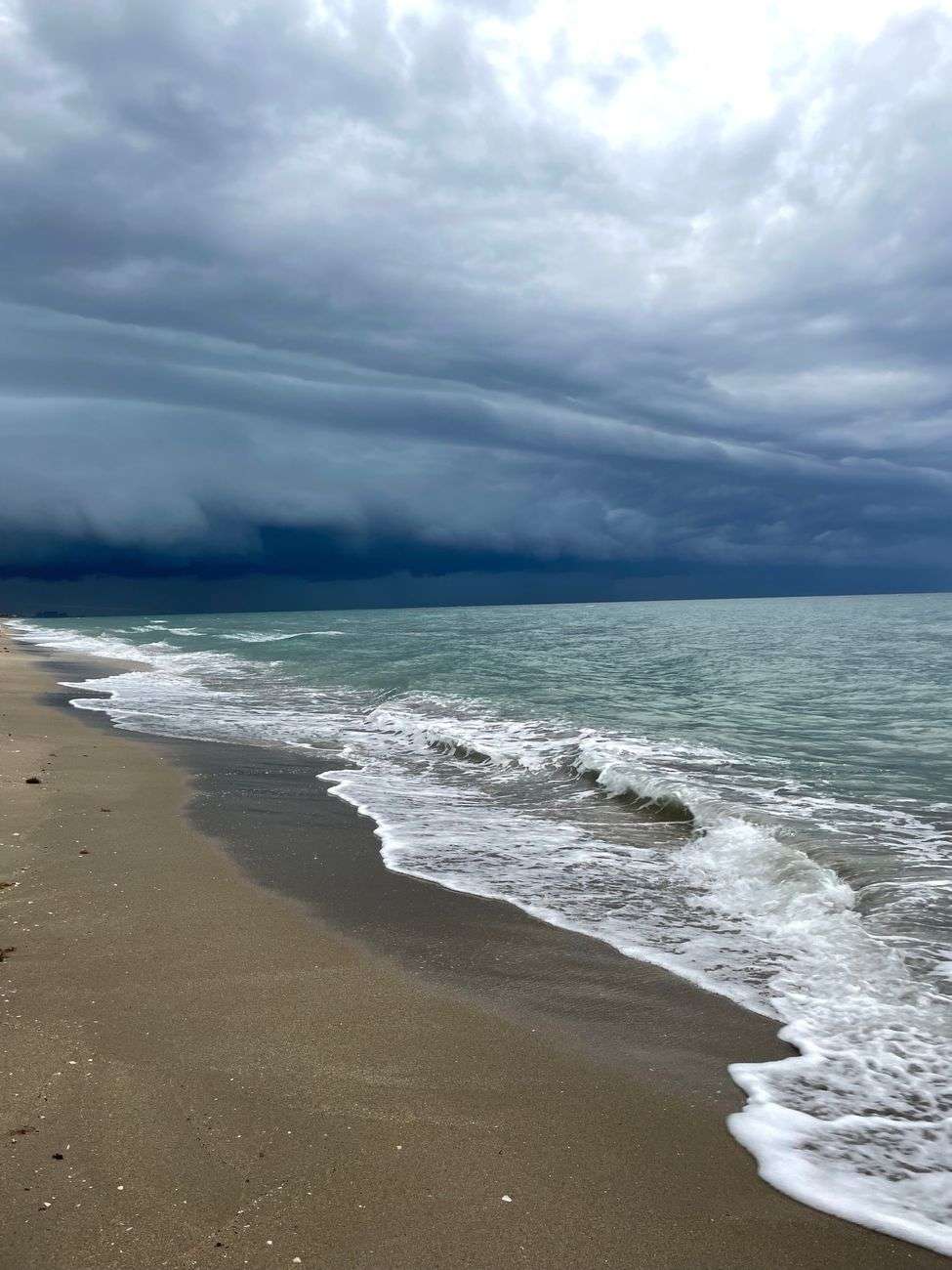Waves washing up onto a beach under a dark, stormy sky