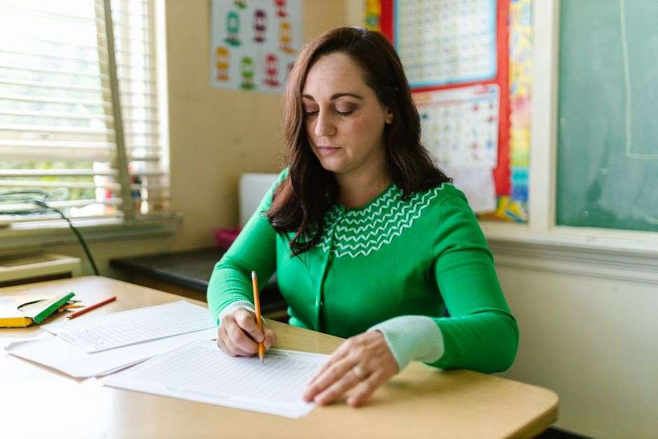 A teacher reviews a classroom test at her desk