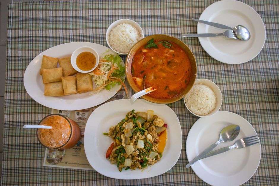 A Thai meal spread featuring curry, rice and spring rolls on a table