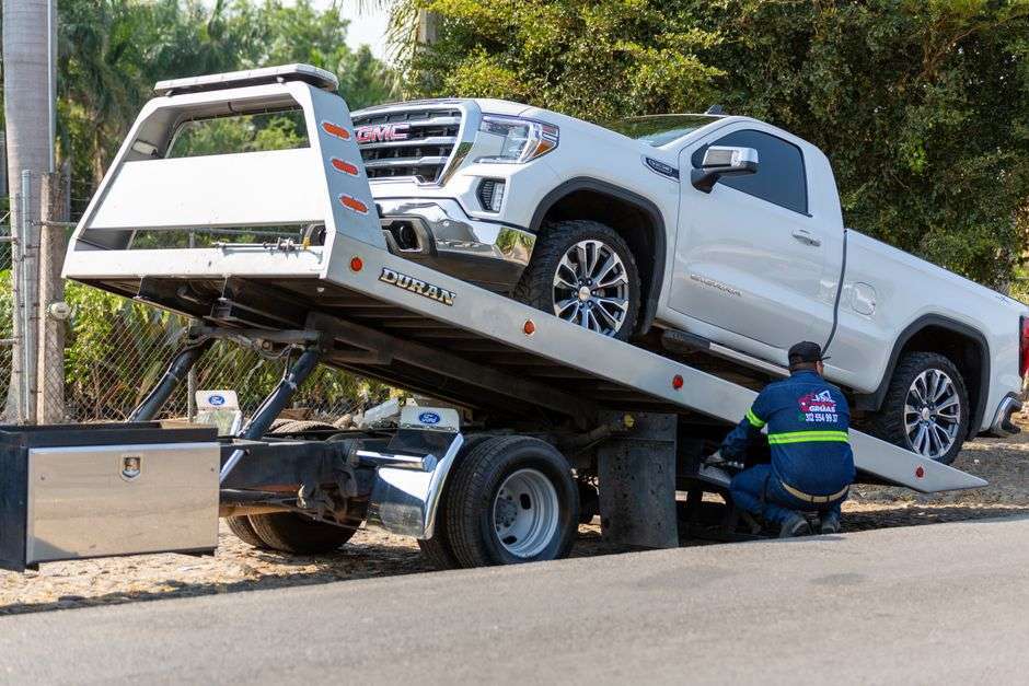 A tow truck operator loading a pickup truck onto a flatbed