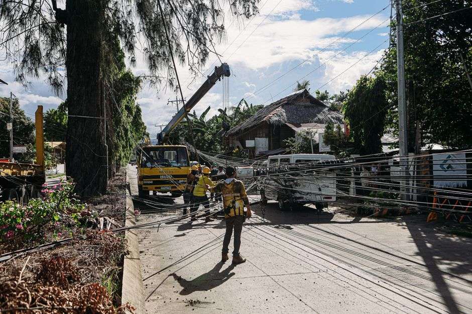 Utility crews repair downed power lines along a roadway in the aftermath of a hurricane