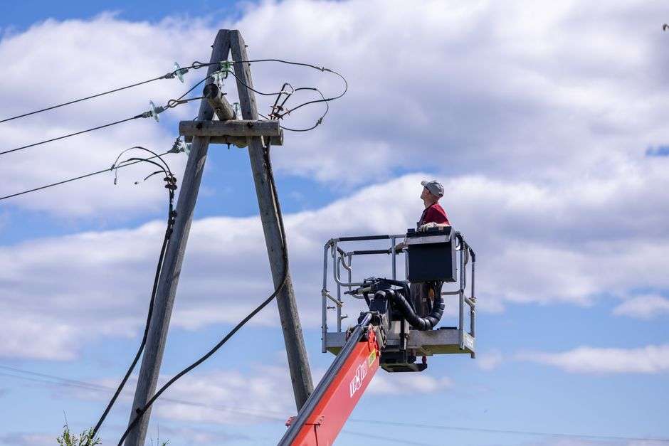 Utility worker on a lift repairing power lines near utility poles
