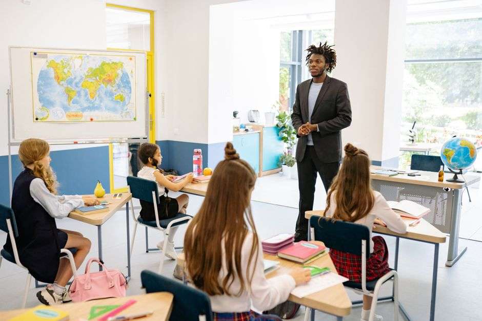 A teacher engages with students in a classroom, part of a veteran-led school education program